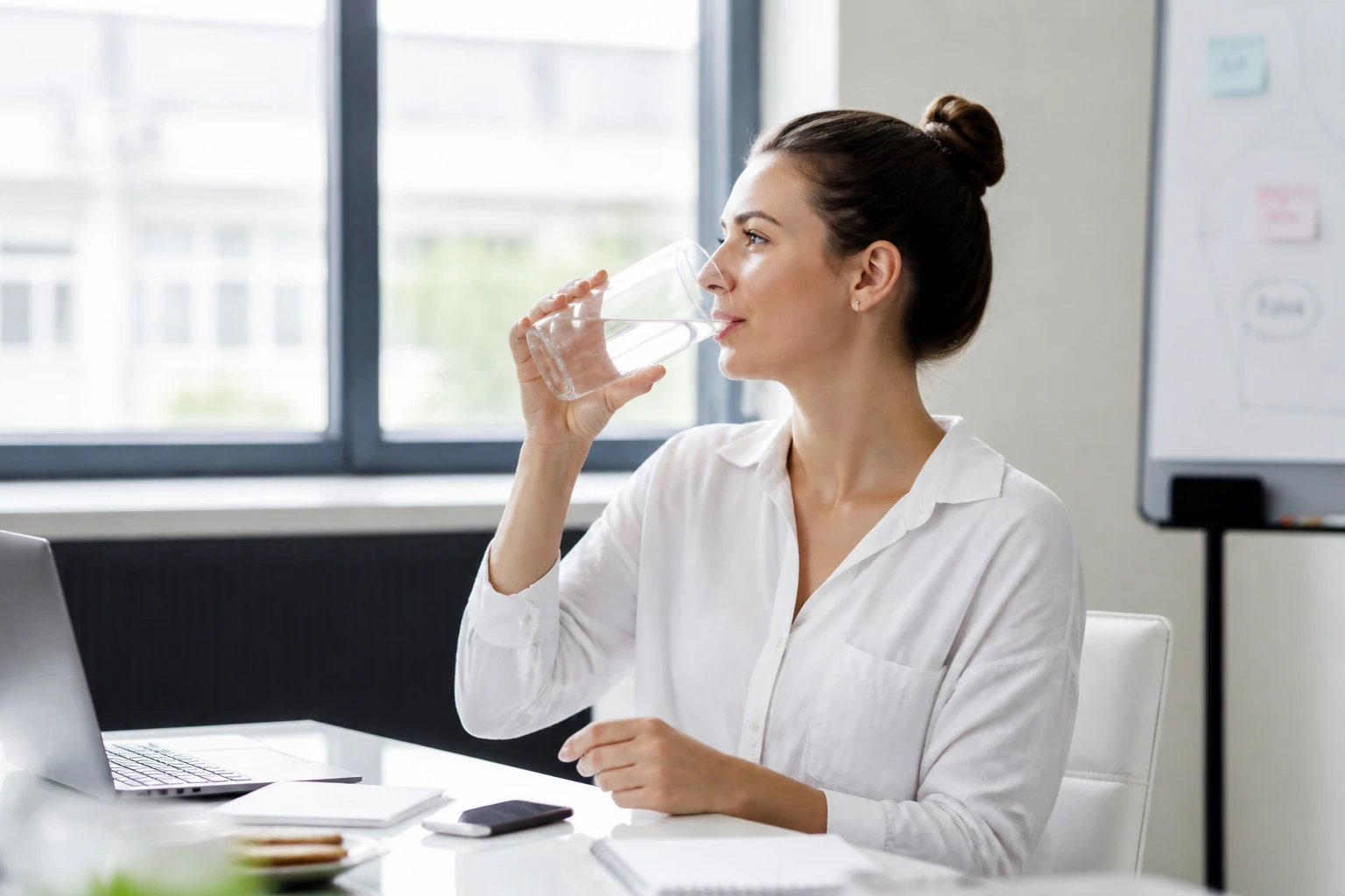 Femme buvant un verre d'eau près d'une fenêtre pour retrouver de l'énergie rapidement